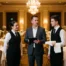 Operations manager briefing a banquet captain and server in a hotel ballroom set for a large event.