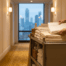 Hands set a folded towel on a housekeeping cart in a warm-lit hotel corridor, with a blurred city skyline in the window